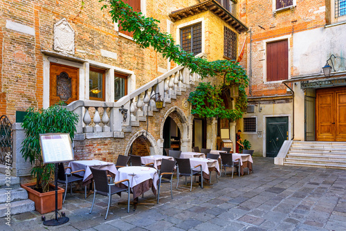 Old street with tables of restaurant in Venice, Italy. Architecture and landmark of Venice. Cozy cityscape of Venice. © Ekaterina Belova