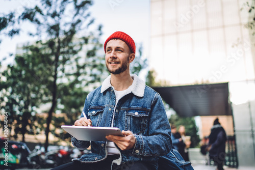 Inspired modern man drawing on tablet on street