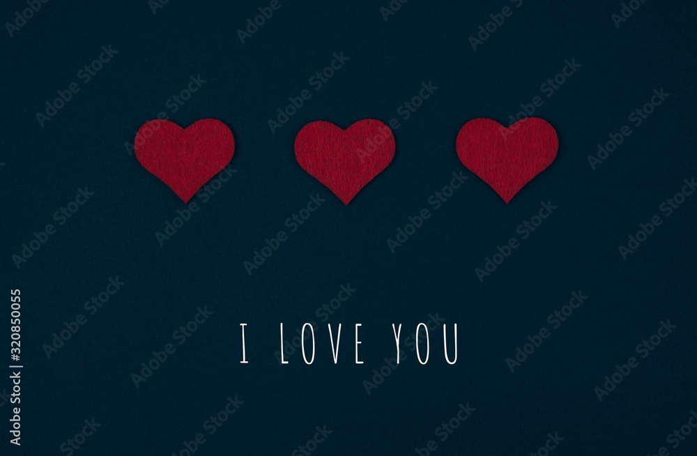 Greeting or invitation card with red hearts over black background with inscription I love you. Top view. Valentines day card.