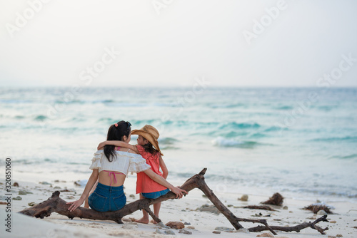 ビーチで流木に座る母と娘
