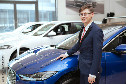 Mature businessman smiling joyfully while examining cars on sale at local dealership, copy pace © Ihor