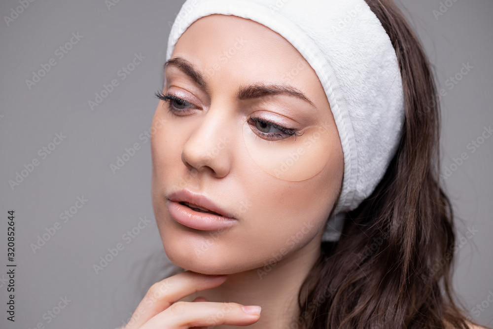 Portrait of Beauty woman with eye patches showing an effect of perfect skin. Beautiful face of young woman with clean fresh skin on gray background. Spa treatment Portrait of Beauty woman with eye patches showing an effect of perfect skin. Beautiful face of young woman with clean fresh skin on gray background. Spa treatment