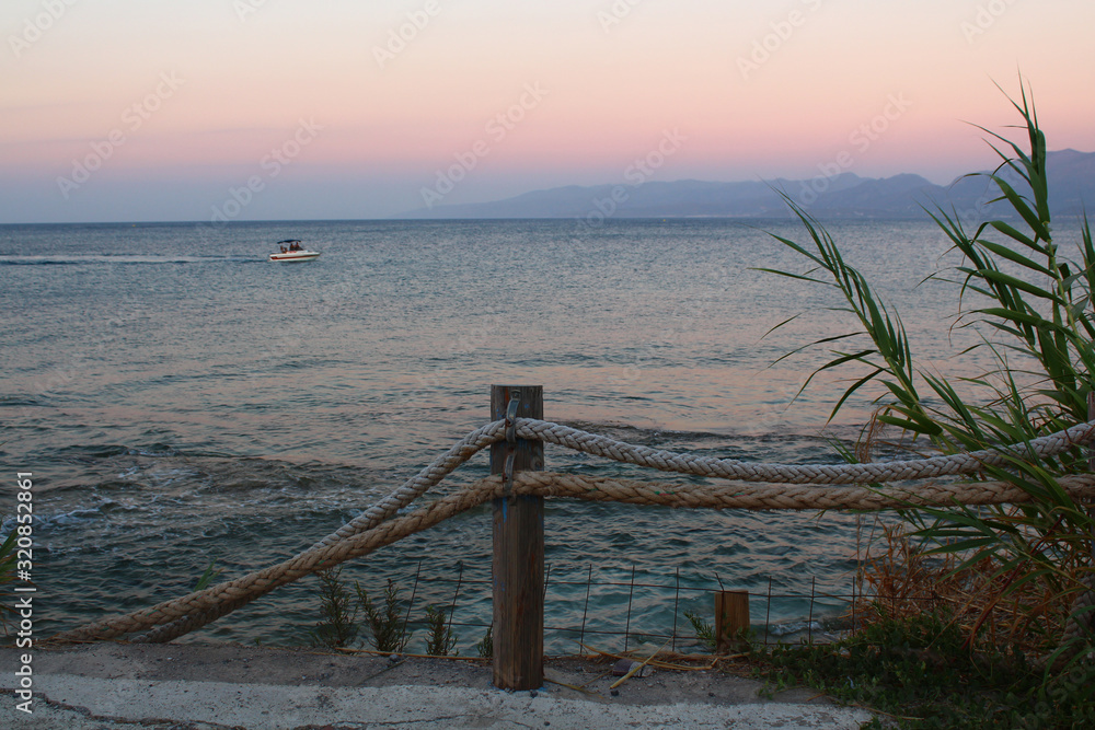 Naklejka premium Greece, Crete. Sea promenade in the evening. Rope fence on the promenade by the sea.