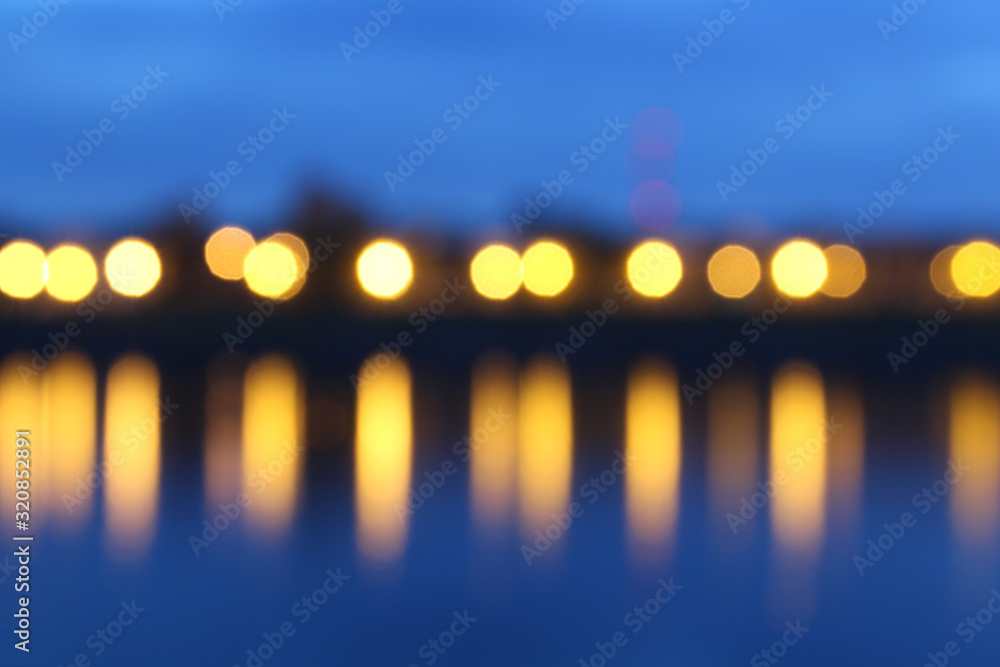 Сolorful city lights with circular bokeh effect reflected on the background of the river at dusk Сolorful city lights with circular bokeh effect reflected on the background of the river at dusk