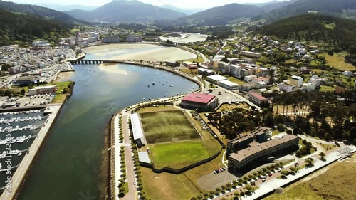 Aerial drone view of Viveiro village and marina and the beautiful beach of Covas just nearby during a sunny summer daytime with the vast mountains in the background photo
