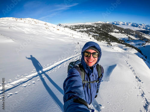 selfie of the mountaineering young man at the summit in the snow covered winter landscape