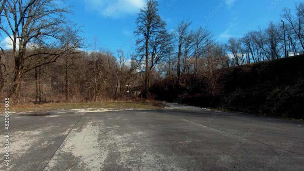 Backward dolly moving on empty parking lot near forest Backward dolly moving on empty parking lot near forest