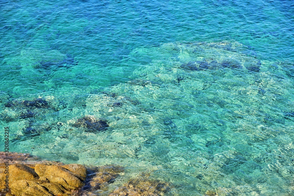 Amazing azure sea water and rocks. Beautiful natural beach with white stones and turquoise water. Halkidiki Greece Blue Flag Beach. Coral reef in the sea. White rocks and blue transparent ocean 