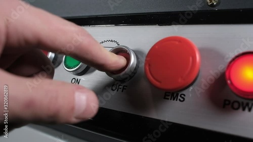 professional worker at furniture factory turns off electric wood cutting machine. man presses Off button with his fingers. The construction and manufacturing sectors. enabling and disabling hardware