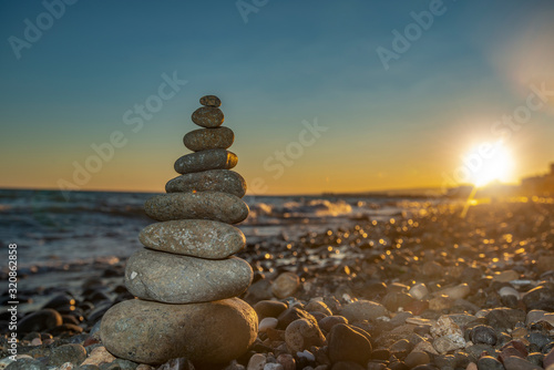 Pyramid of stones on the beach at sunset,