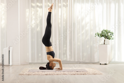 Fotografie Young woman making a headstand on a mat