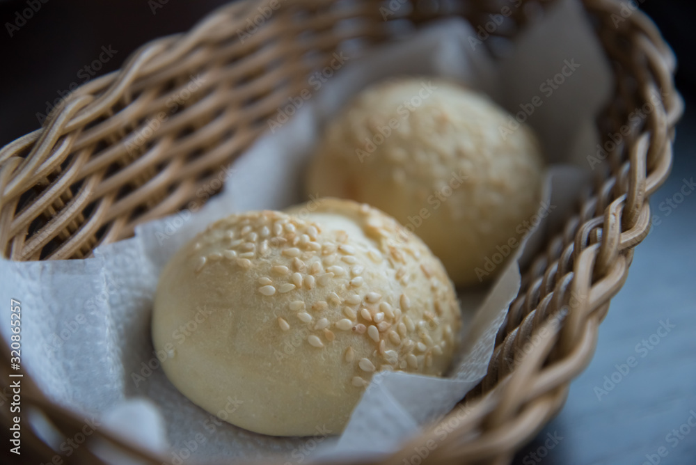 Two sesame buns are in the bread basket. Bread close-up. Two sesame buns are in the bread basket. Bread close-up.