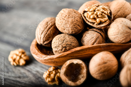 Whole walnuts on dark board, Walnut kernels in wood rustic bowl.