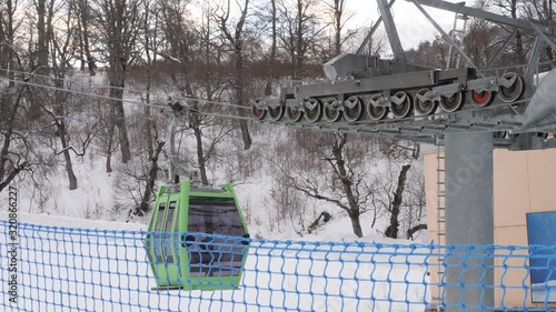 Green ski lift cabin moving at winter. Ski lift station and blue protection net