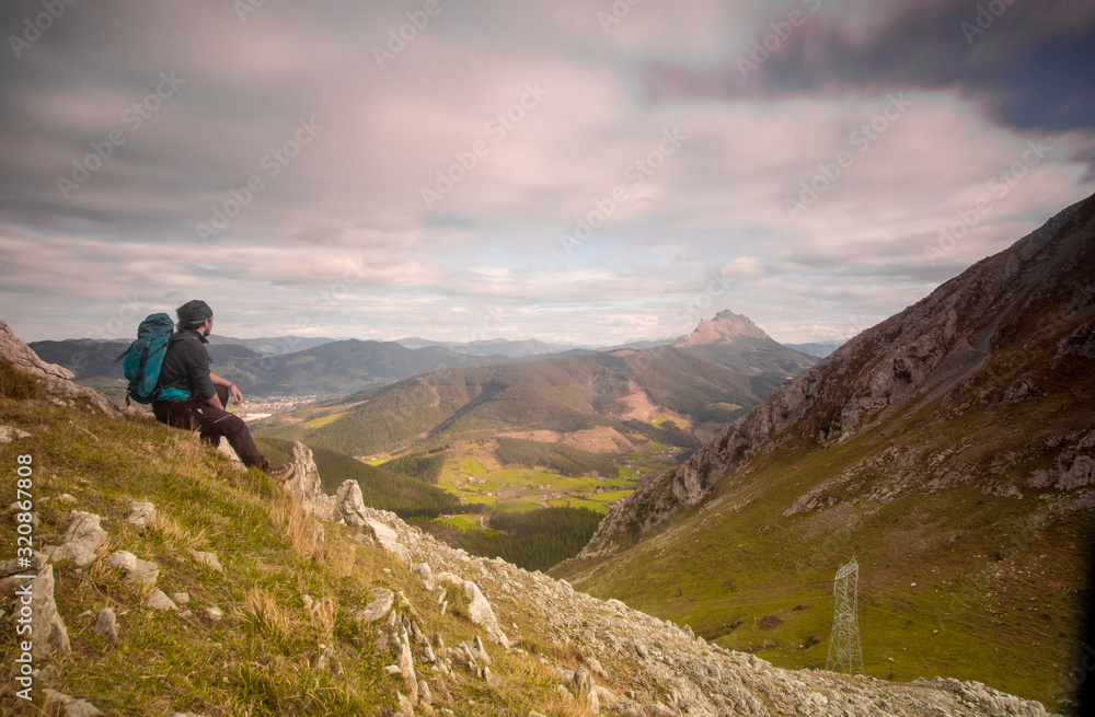 man sitting down looking the mountains in basque country, spain