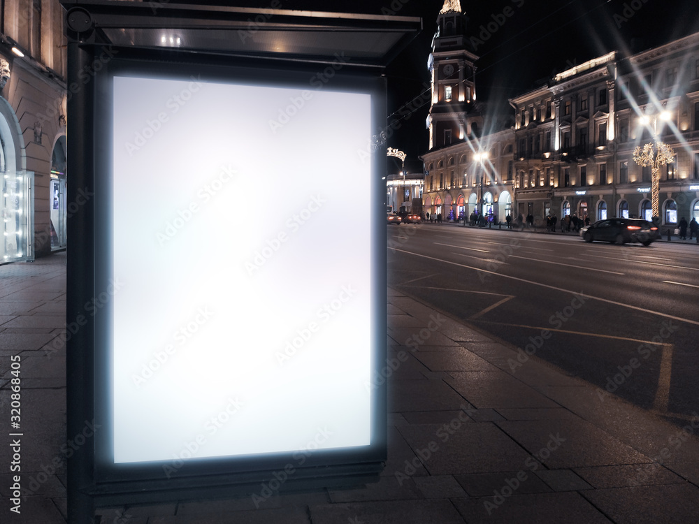 billboard in a bus stop. Glowing box with an advertising poster standing in the city at night.
