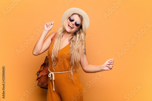 Foto young pretty latin woman smiling, feeling carefree, relaxed and happy, dancing and listening to music, having fun at a party