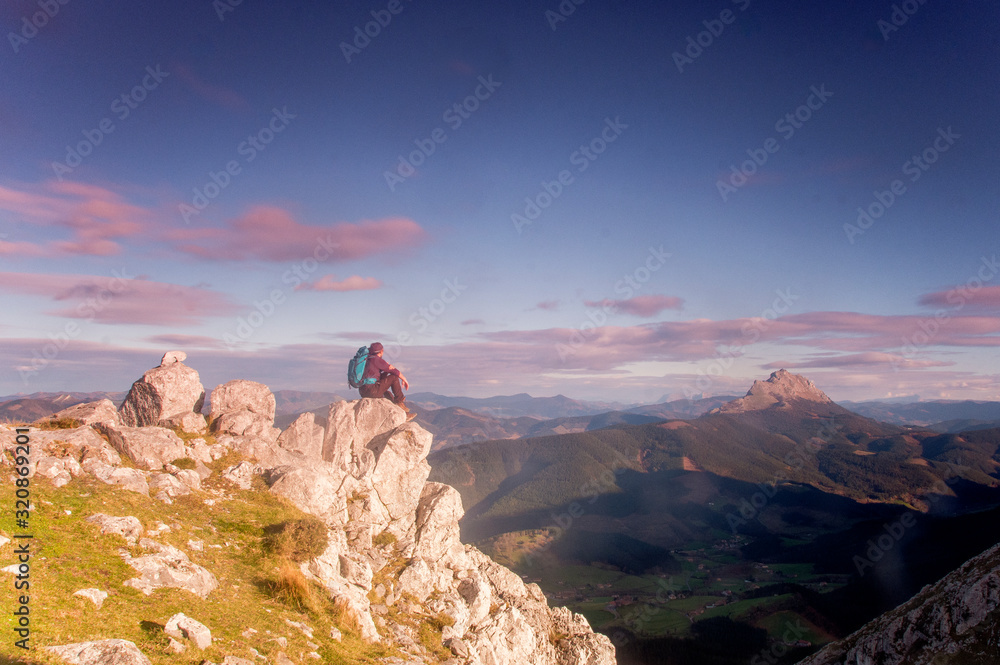 Naklejka premium man sitting down on the mountains looking the horizon