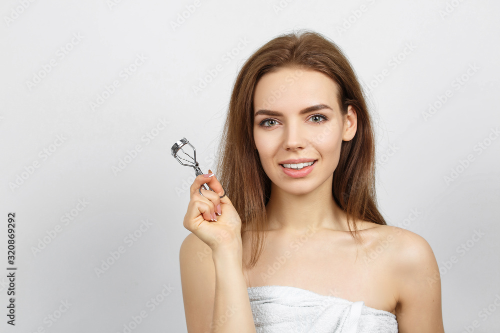 Smiling woman in a towel with Eyelash curler Smiling woman in a towel with Eyelash curler