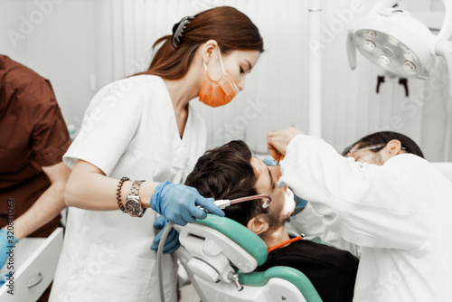 Two dentists treat a patient. Professional uniform and equipment of a dentist. Healthcare Equipping a doctor   s workplace. Dentistry