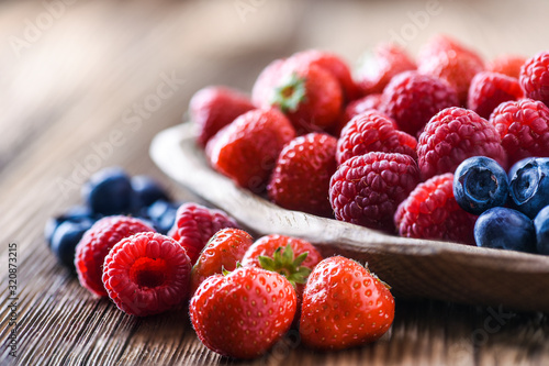 Forest fruits in wooden bowl. Blueberries  raspberries  strawberries on vintage table.