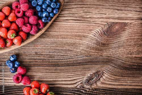 Fototapeta Naklejka Na Ścianę i Meble -  Forest fruits in wooden bowl. Blueberries, raspberries, strawberries on vintage table.