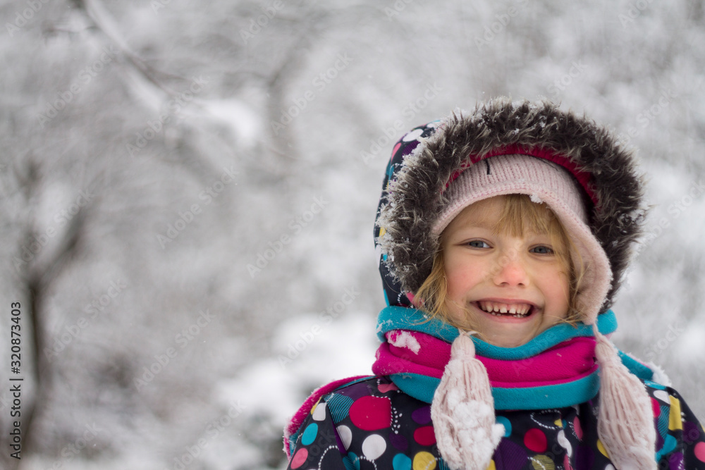 portrait caucasian Pretty happy little girl in modern winter clothes playing in the snow and enjoying winter