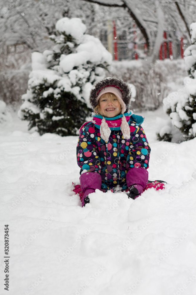 portrait caucasian Pretty little girl in modern winter clothes playing in the snow and enjoying winter
