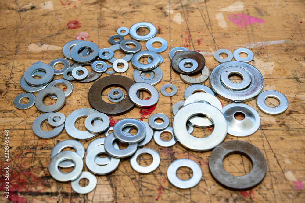 Assorted washers on  wooden workbench stained grunge textured surface.