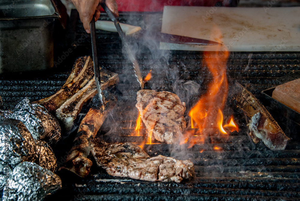gril grill with roast beef and fire flames, chef cook food on the fathoms, charcoal-roasted food on hot fathoms in restaurant gril grill with roast beef and fire flames, chef cook food on the fathoms, charcoal-roasted food on hot fathoms in restaurant