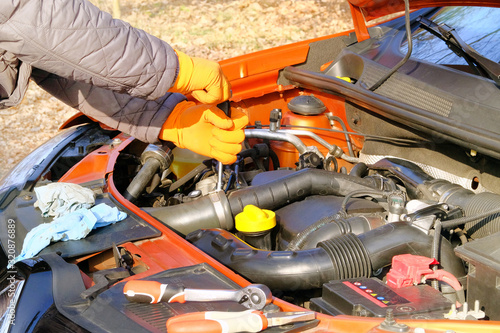 Wallpaper Mural Hands of driver in orange rubber gloves checks car, open hood. Cars and transportation, close up. Problems with car on road while traveling. Torontodigital.ca