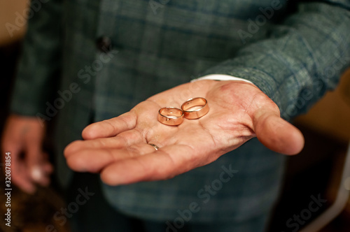 Groom holding golden wedding rings on the hand