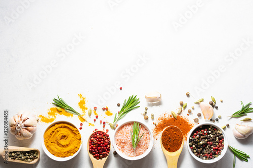 Fototapeta Bright aromatic set of spices on white marble table top view with copy space for your text.