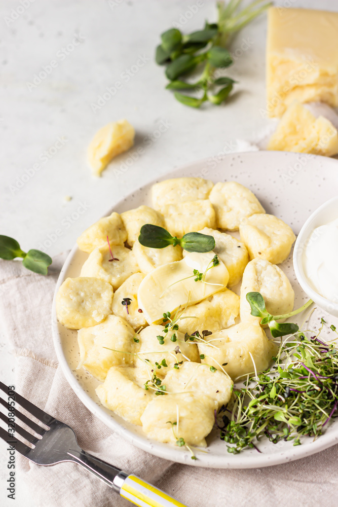 Curd and cheese dumplings served with microgreens and sour cream on a ceramic plate. Traditional Ukrainian or Russian lazy dumplings (vareniki). Healthy breakfast. 