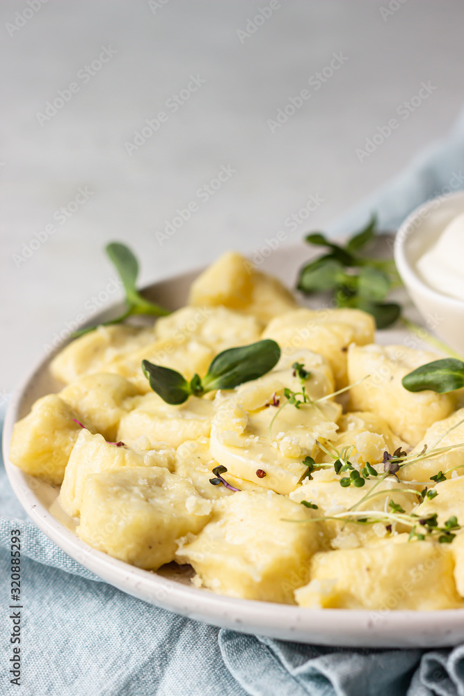 Curd and cheese dumplings served with microgreens and sour cream on a ceramic plate. Traditional Ukrainian or Russian lazy dumplings (vareniki). Healthy breakfast. 