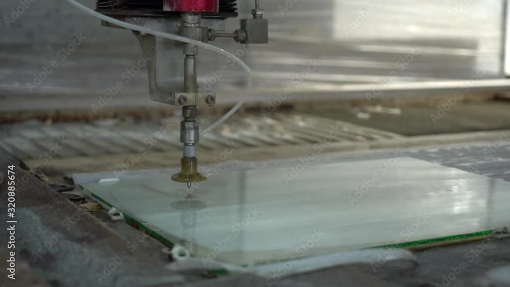 Metal water-jet machine at work. Slowmotion of an automatic water jet cutting machine cutting glass panel to the desired shape. CNC machine in a glass factory. Metal water-jet machine at work. Slowmotion of an automatic water jet cutting machine cutting glass panel to the desired shape. CNC machine in a glass factory.