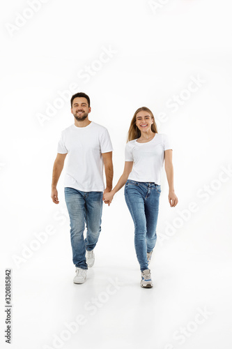 full length portrait of happy couple in casual outfit walking forward together on white background