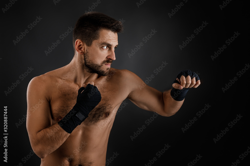 Sportsman boxer throwing a fierce and powerful punch. muscular man on black background.