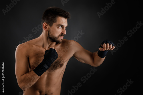 Sportsman boxer throwing a fierce and powerful punch. muscular man on black background. © producer