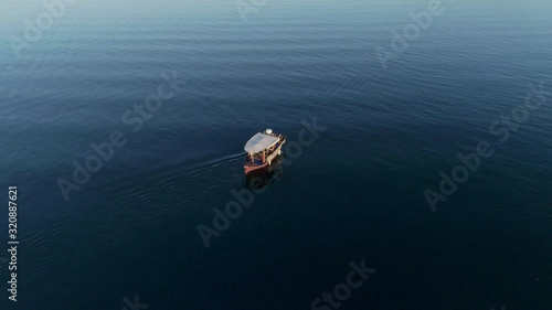 Aerial top view of a boat sailing slowly along the deep blue waters of the Ambracian Gulf in Greece, drone footage photo