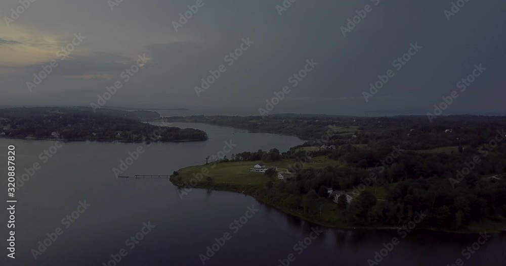 Homes and docks along the coastline of Penobscot Bay in Maine during sunset.