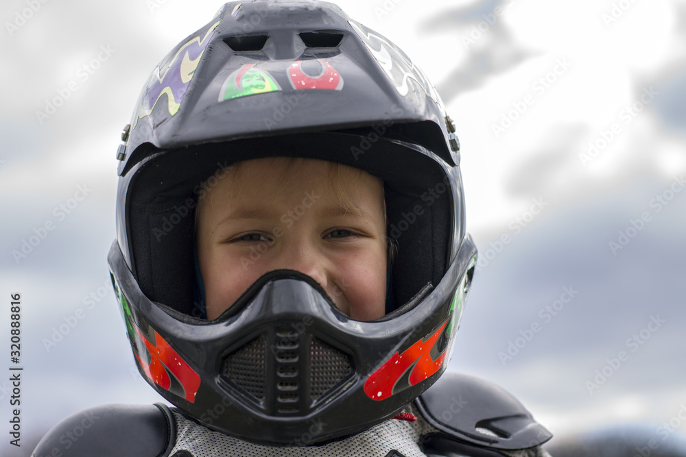 portrait of a little girl smiling in a protective helmet female child in motocross moto helmet . biker girl in motocross helmet portrait of a little girl smiling in a protective helmet female child in motocross moto helmet . biker girl in motocross helmet