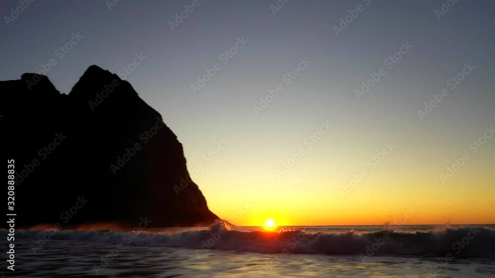 Aerial, reverse, drone shot panning over waves at the Kvalvika beach, at sundown, on a sunny, summer evening, in the Lofoten islands, in Norway Aerial, reverse, drone shot panning over waves at the Kvalvika beach, at sundown, on a sunny, summer evening, in the Lofoten islands, in Norway