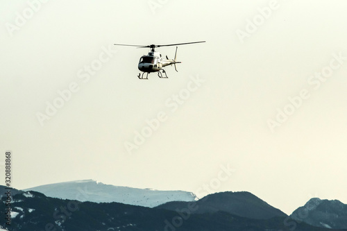 An atmospheric picture shows the helicopter climbing in front of the high snowy mountains. 