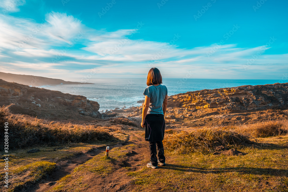 A young woman looking at the coast and the sea of the Jaizkibel mountain near San Sebastian, Gipuzkoa. Spain