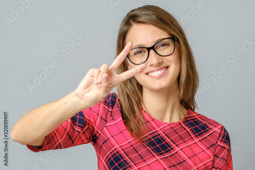 Cheerful woman showing peace sign with her fingers