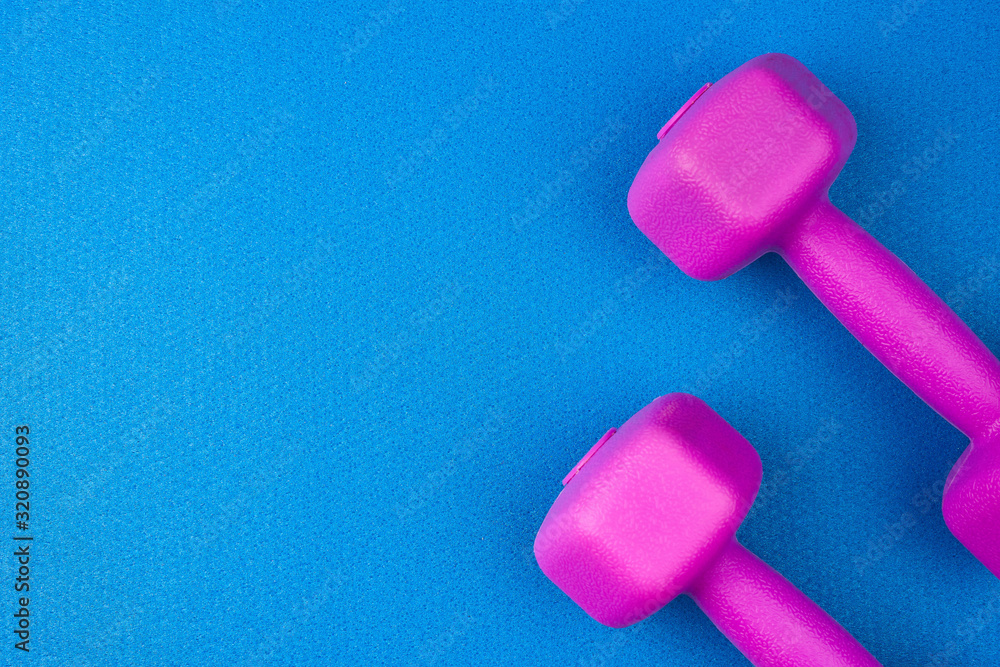 pair of purple plastic dumbbells on a blue neoprene mat pair of purple plastic dumbbells on a blue neoprene mat