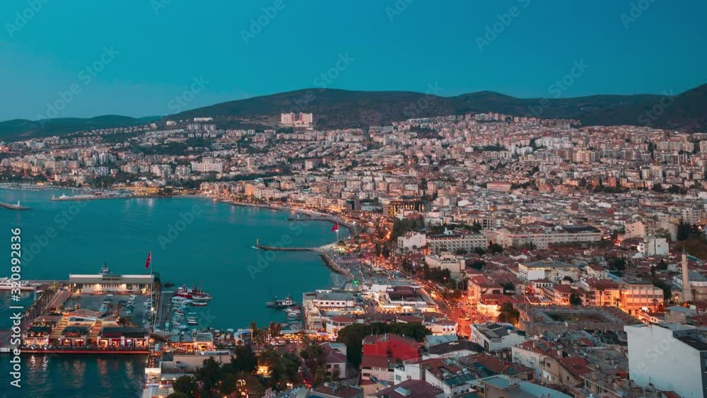 Kusadasi, Aydin Province, Turkey. Waterfront And Kusadasi Cityscape In Summer Evening. Night Scenic View Of Kusadasi Skyline At Aegean Coast, Turkey. 4K Kusadasi, Aydin Province, Turkey. Waterfront And Kusadasi Cityscape In Summer Evening. Night Scenic View Of Kusadasi Skyline At Aegean Coast, Turkey. 4K