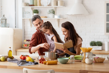 Happy mother and father watching daughter cooking