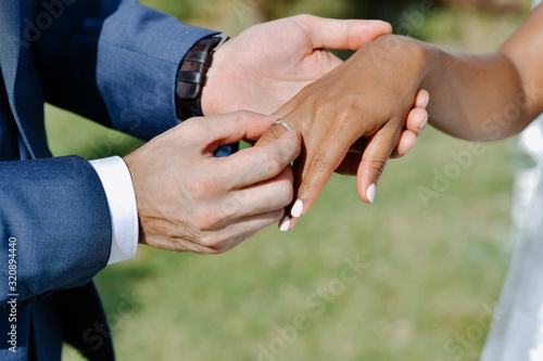 Ceremony of putting the wedding ring on the bride's finger outdoors